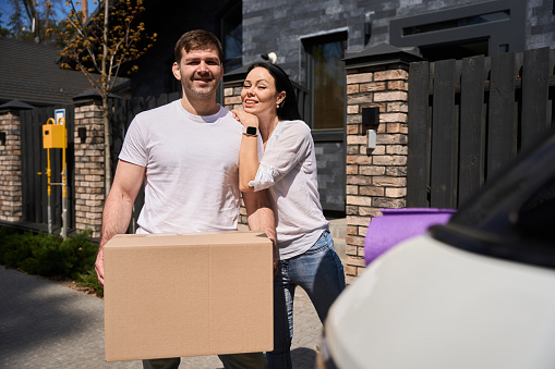 Wife hugging her husband while he holds the moving box