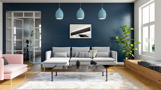 Modern living room setup with dark blue walls, white sofa, pink modern arm chair, wooden coffee table and carpet.