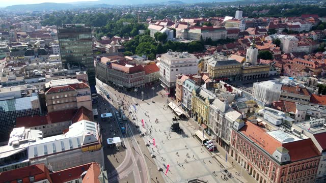 Aerial shot drone orbits to the right around main plaza Trg bana Josipa Jelačića in Zagreb, Croatia