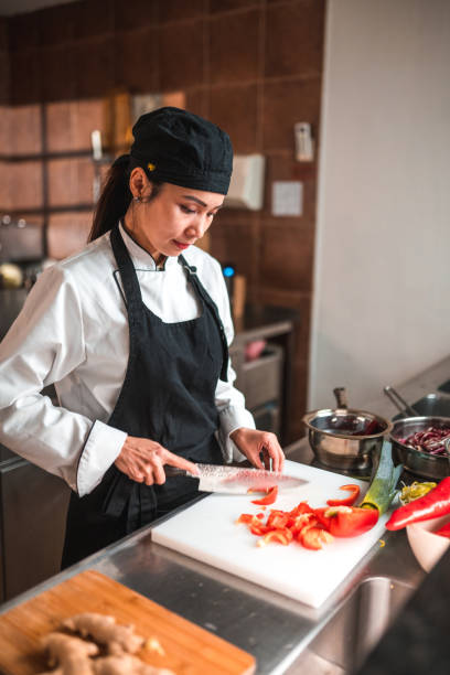 istock Female Chef Dicing Red Peppers in Bright Kitchen 1507973757