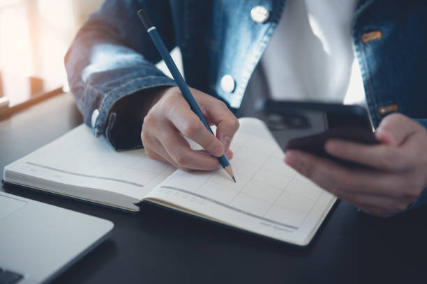 istock 2023 Calendar event planner timetable agenda plan on organize schedule. Business woman using mobile phone with monthly calendar for event planning, Plan scheduling on notebook on office table 1508084840