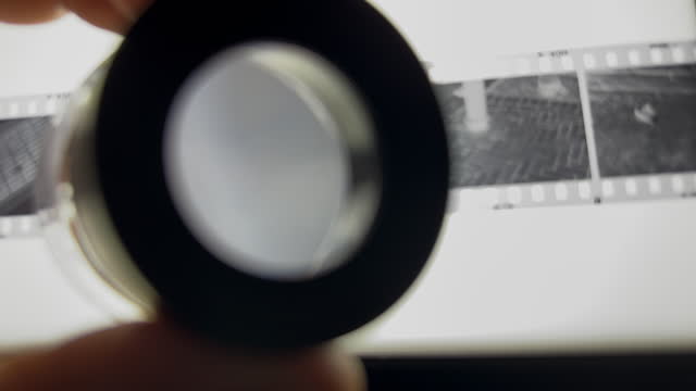 POV Examining Film Negative On Light Box Through Loupe