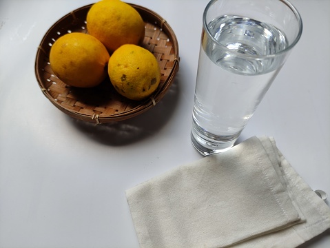 a glass filled with mineral water and fresh lemons on a white background
