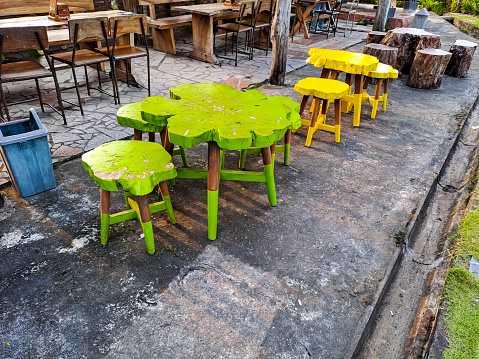 Bright color of wooden chair and table in the terrace of outdoor cafe with green garden and rice field in the background