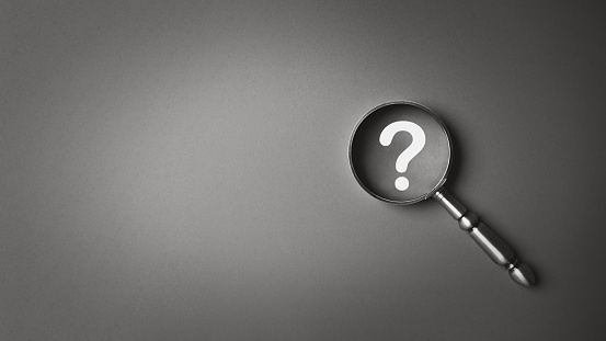 Black and white magnifying glass and question mark icon symbol on gray paper background with copy space. Problem solving troubleshooting education concept.