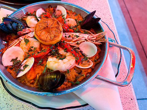Paella is a traditional Spanish dish made with short-grain rice, saffron, and various ingredients such as chicken, seafood, and vegetables. It is cooked in a wide, shallow pan called a \