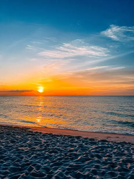 Miami Beach, Florida, USA as the soft morning sun rises above the edge of the Atlantic Ocean, illuminating the sky with its warm and glowing colors.