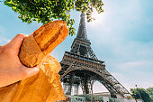 Caucasian Tourist Man's Hand Holding a Jambon-Beurre while Standing in the Shade under the Eiffel Tower