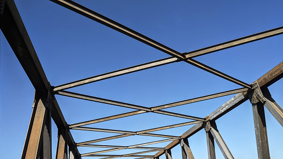 Steel frame construction on pedestrian bridge in daytime with blue sky background