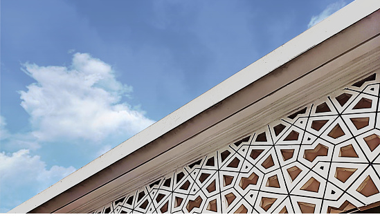 White Islamic Roster and Ornament seen from below in perspective and cloudy sky background.