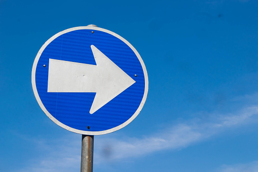 Blue road sign pointing direction on a light background