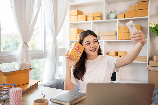 Entrepreneurial Woman Takes Selfies with Products for Online Sales, Working from Home, Identity Verification and Order Confirmation in Online Business, Capturing the Essence of Entrepreneurship.
