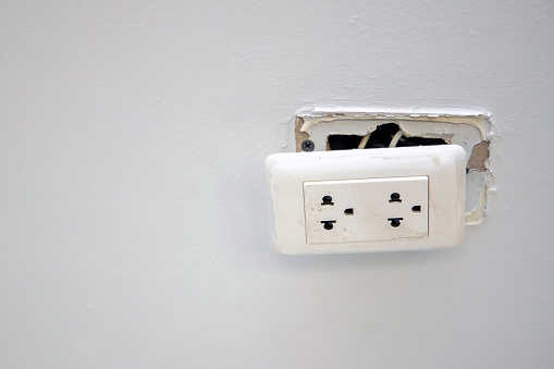 Broken dangerous electric outlet plug on the wall with empty space. Dangerous of electric from short circuits and fire in house.
