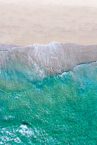 Beautiful quiet white beach background with emerald green waters. Aerial view from above of sea and sand.