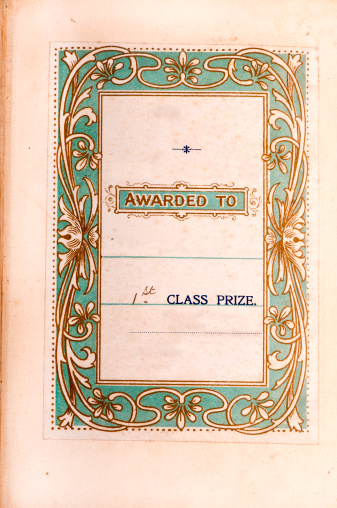 Printed insert dedicating a book as a first prize with an art nouveau style border on a pale green background.  About 100 years old.  Photo insitu in ton the first page of the book.