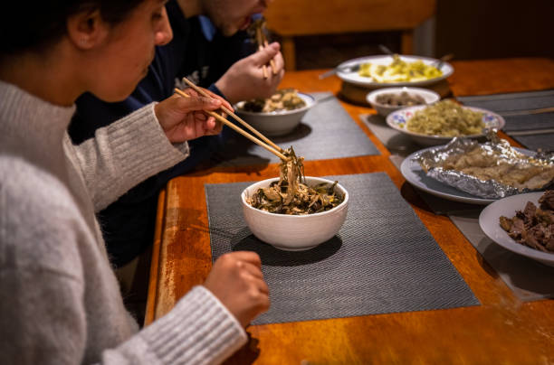 istock Couple holding chopsticks and eating dinner. Vegetable and beef dishes on the dinner table. Home cooking and eating concept. 1508541429