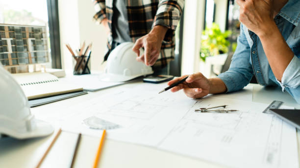 Two engineer working to discuss and collaborate about blueprint of construction project in office