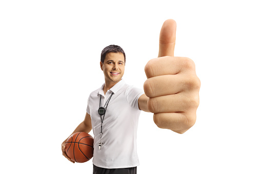 Basketball coach holding a ball and showing a thumb up sign isolated on white background