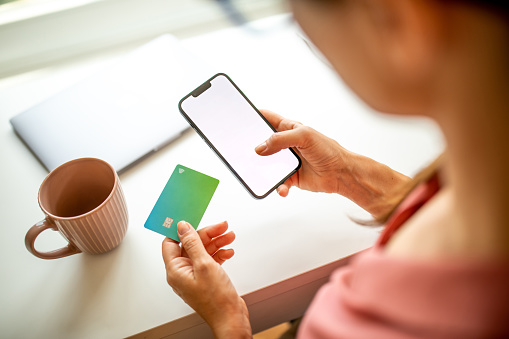 Woman using her credit card to shop online on her laptop and phone stock photo