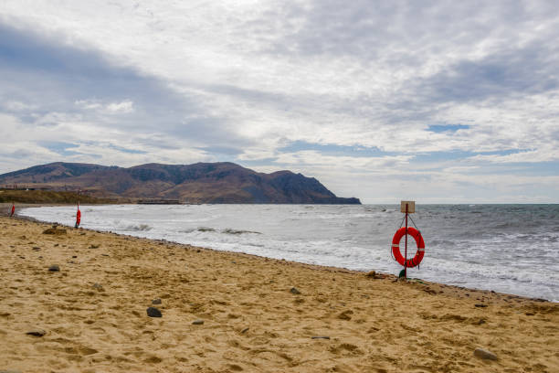 Several lifebuoys on the sandy Black Sea beach Raketa. Cape Rybachy of the Meganom Peninsula is in the background. Valley Kapsel, Crimea.