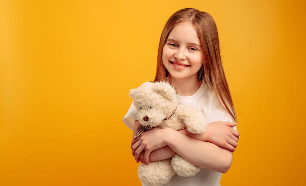 istock Girl with teddy bear isolated on yellow background 1508610246