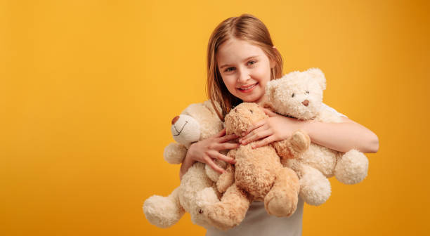 istock Girl with teddy bear isolated on yellow background 1508610257