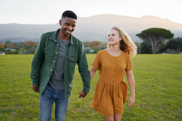 istock Young multiracial couple smiling and holding hands while walking through field 1508628684
