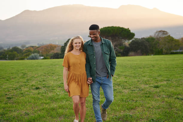istock Happy multiracial young couple smiling and holding hands while walking in field 1508629893