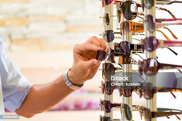 Giovane Uomo In Ottico Shopping Occhiali Da Sole - Fotografie stock e altre immagini di Occhiali da sole - Occhiali da sole, Fare spese, Vendita al dettaglio