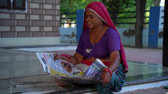 Footage of senior woman reading newspaper. Indian woman reading newspaper at home.