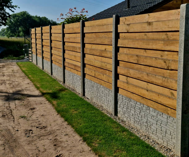 istock garden fencing where materials such as wood and rectangular concrete blocks are combined. between the walls are embedded pieces with planks. wet after rain, lawn roll 1508699292