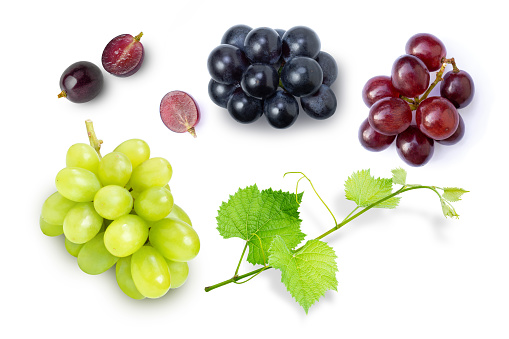 Various grapes and half sliced with grape leaf isolated on white background. Top view. Flat lay.