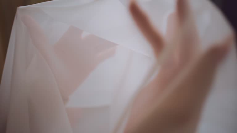 closeup of female hands choosing fabric for curtain tulle at textile showroom