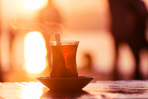 Traditional Turkish tea in a glass against the background of sunrise lights near Bosphorus embankment