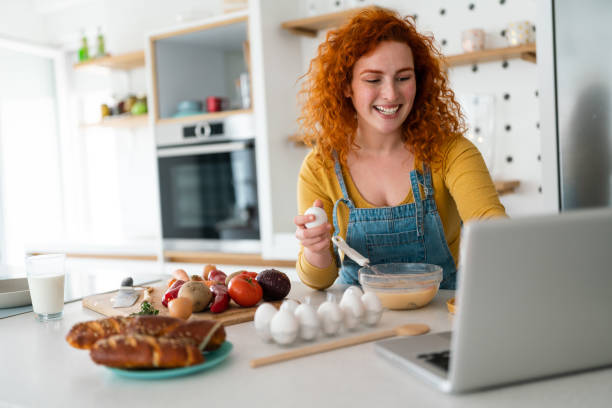 istock Woman looking at laptop in kitchen while preparing healthy breakfast 1508744025