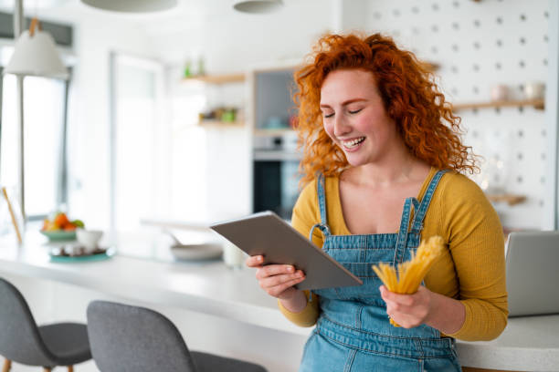 istock Smiling woman looking at digital tablet for recipes with spaghetti 1508745058