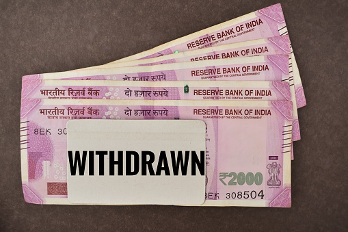 A closeup Picture of Withdrawn Indian two thousand rupees bank currency notes with Text Withdrawn on card.