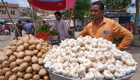 Beawar, Rajasthan, India, July 1, 2023: Vegetable vendors waits for customer at a market in Beawar. Vegetable prices have soared across India. Retail price of tomato at Rs 100-120/kg, Garlic at Rs 180-200/kg and Ginger at Rs 240-300/kg in many parts of the country.