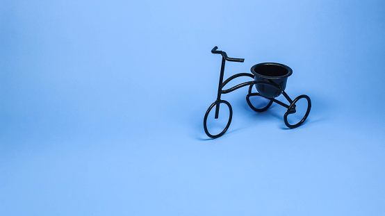 Small black tricycle replica toy isolated on soft light blue color background. Panoramic banner background with blank copy space. a banner with space for text or insertion.