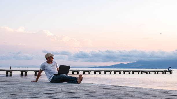 Man working with laptop on pier stock photo