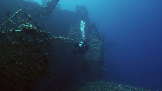 Scuba diver swim along hull of ferry Salem Express shipwreck, Back view, Red sea, Safaga, Egypt