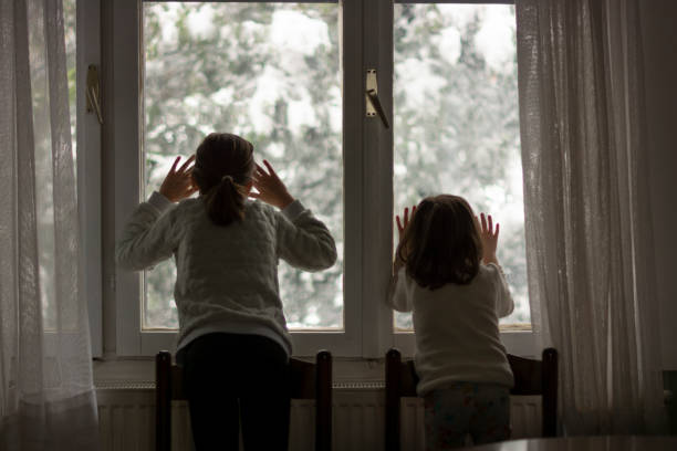 istock Two girls looking through the window at snowy day 1508833136