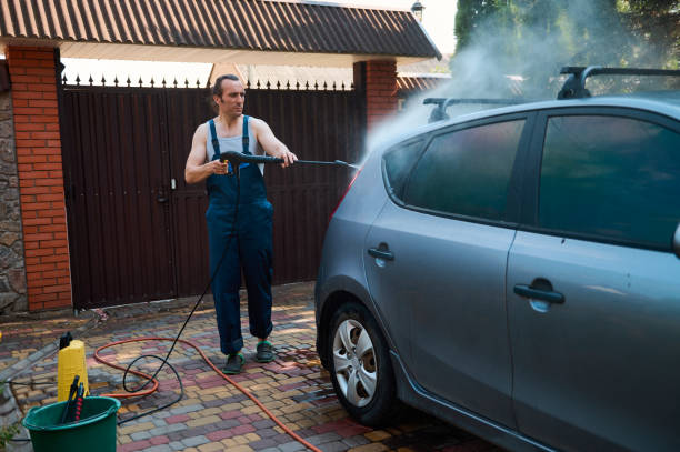 istock Full length handsome Caucasian man in blue work uniform, washing car using water high pressure cleaner in the backyard 1508847173