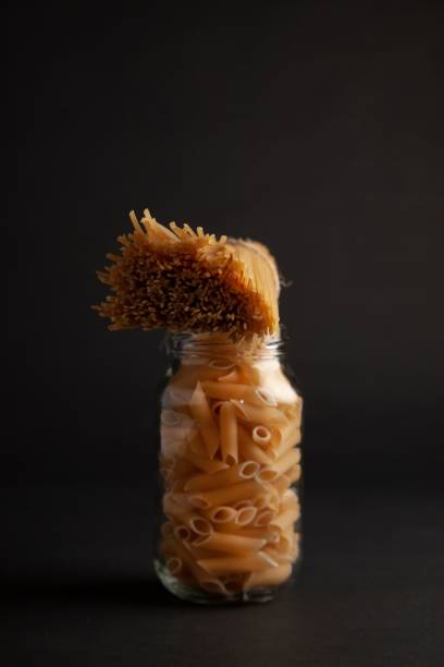 Clear glass jar containing raw pasta with tied pasta on top