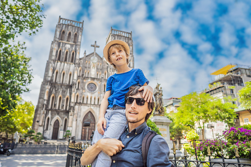 Young dad and son tourists on background of St Joseph's Cathedral in Hanoi. Vietnam reopens after coronavirus quarantine COVID 19.