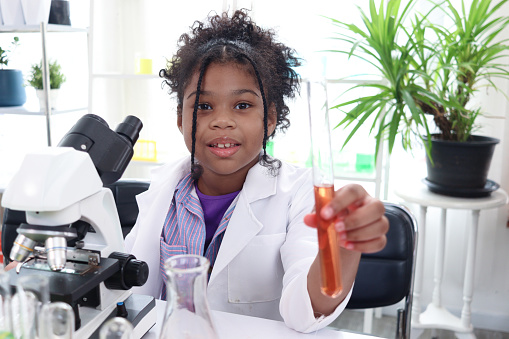 Primary school African curly hair girl does chemistry science experiment in laboratory, cute scientist kid holds chemical test tubes, child use lab equipment to learn biologics, chemistry in classroom
