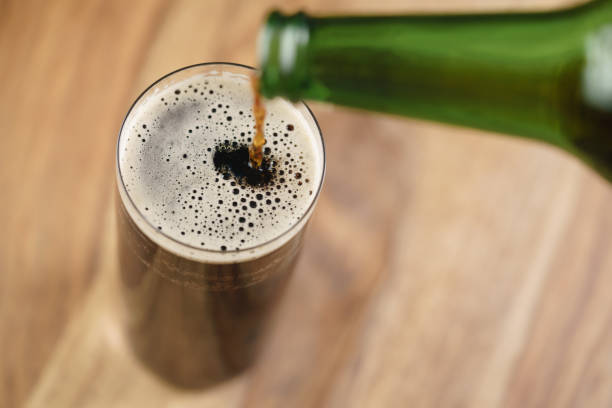istock dark beer pouring in glass on wood table from above 1508905054