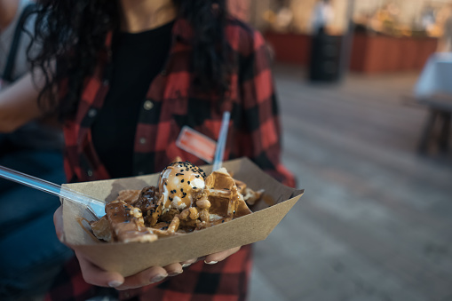 Woman has tasty Belgian waffles with ice cream and caramel
