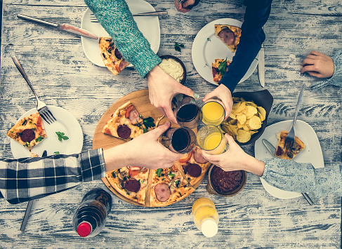 people clanging glasses together having pizza top view