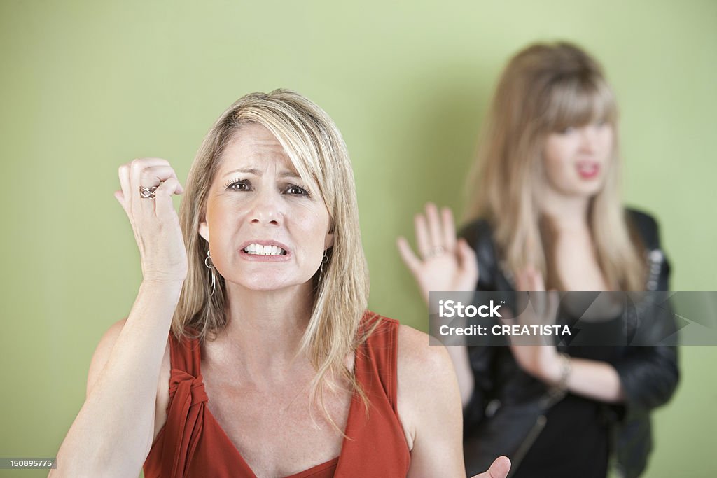 Upset Mother and Daughter Unhappy mother with frustrated daughter over green background Adult Stock Photo